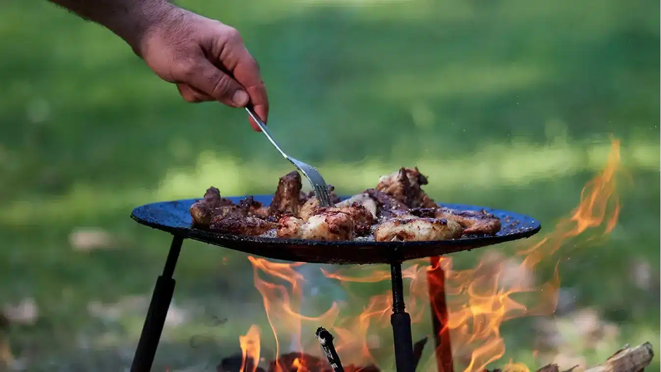 hús sütése grillező tárcsán nyílt tűz felett